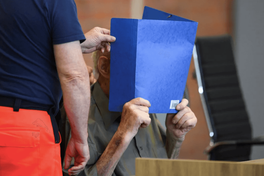 Йозеф Шютц на всех фотографиях из суда закрывает лицо папкой