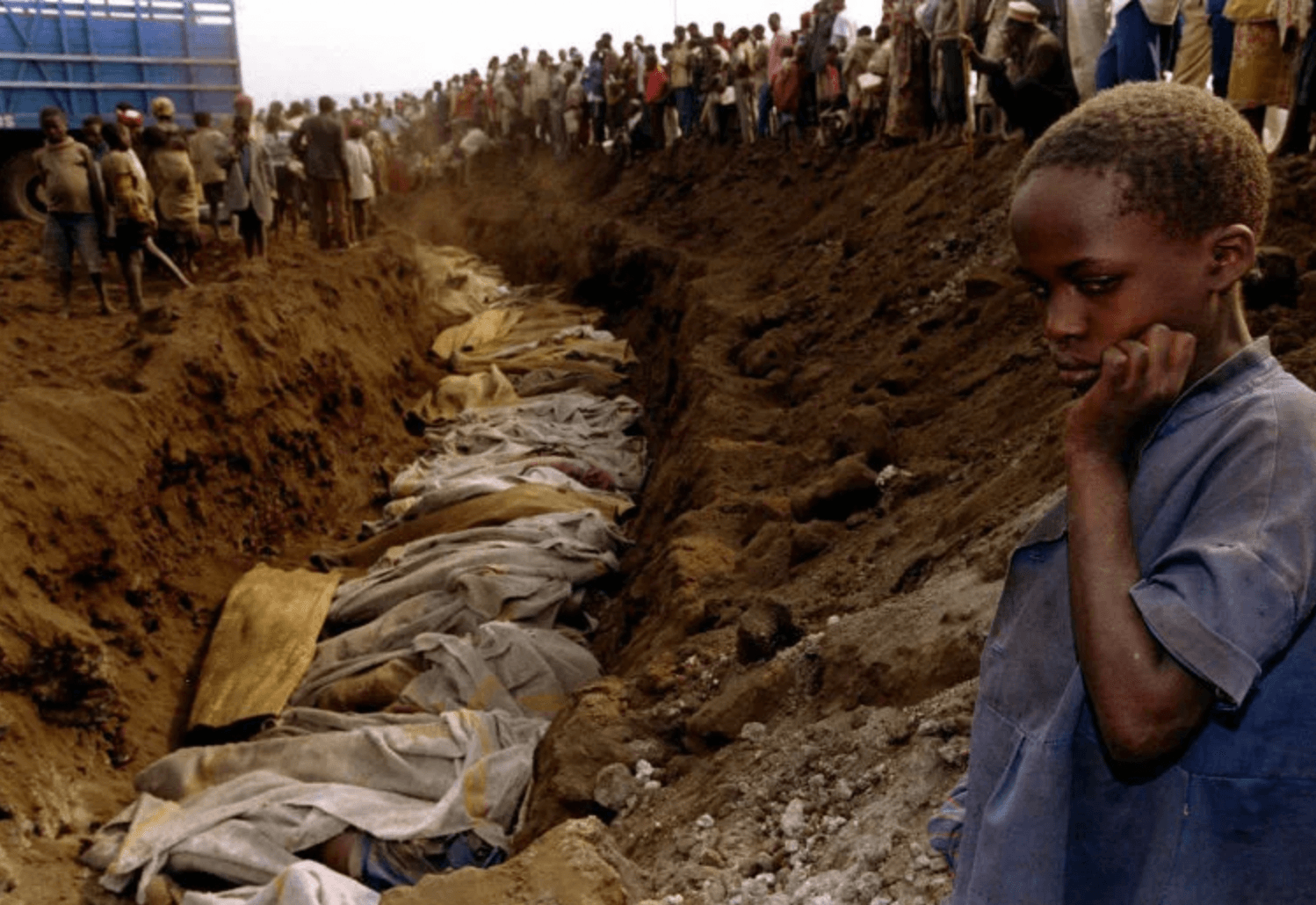 Мальчик тутси на фоне братской могилы, в которой похоронены все его родные